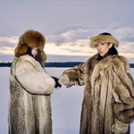 Duo Cartel Madras are posed in a vast snow covered terrain, both wearing heavy fur coats and hats.