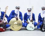 Photo of four-piece Etran de L'Aïr posed sitting with their instruments, each wearing traditional Nigerien wear