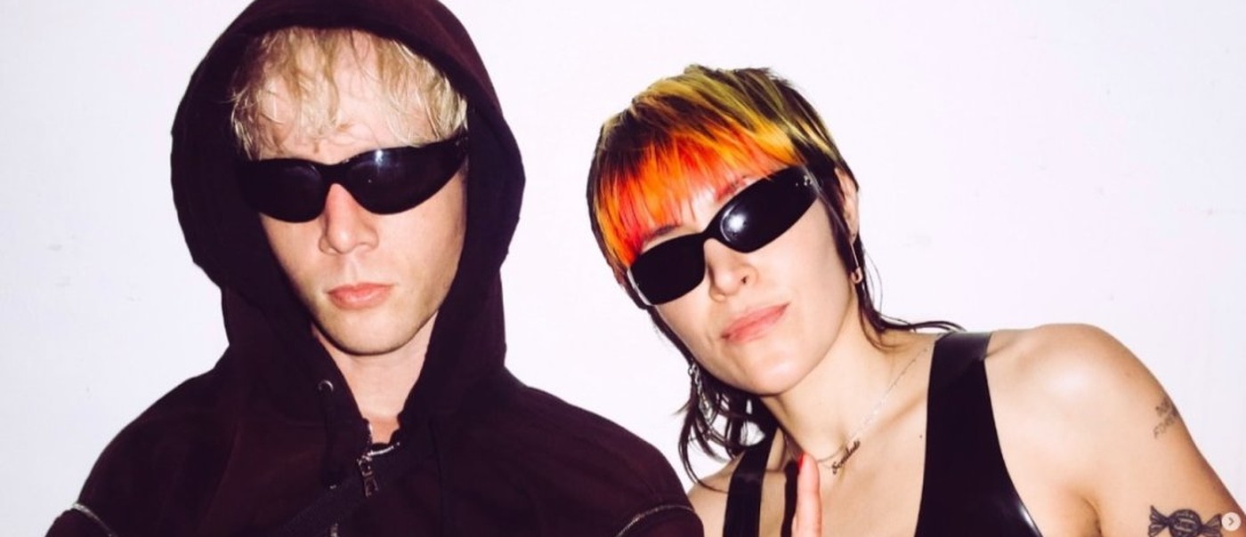 Duo Sextile are both in dark sunglasses, faced toward the camera, with a neutral background