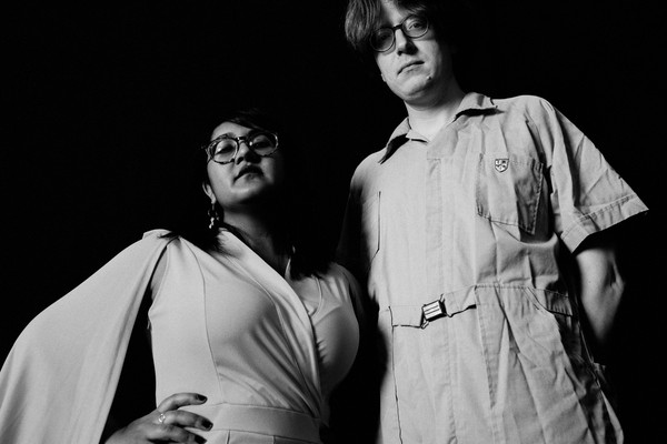 Black and white photo of duo Sweeping Promises, standing posed with their gaze downward toward the camera.