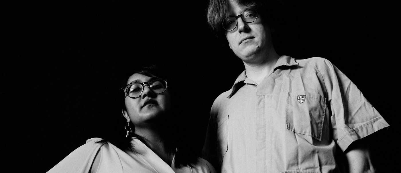 Black and white photo of duo Sweeping Promises, standing posed with their gaze downward toward the camera.