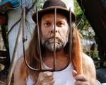 Photo taken outdoor of Thor Harris holding a pitchfork in one hand with a carrot in the other.