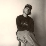 Photo taken of solo artist HOMESHAKE posed seated in a chair, wearing a baseball cap