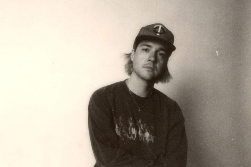 Photo taken of solo artist HOMESHAKE posed seated in a chair, wearing a baseball cap
