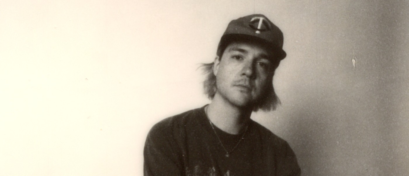 Photo taken of solo artist HOMESHAKE posed seated in a chair, wearing a baseball cap
