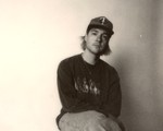 Photo taken of solo artist HOMESHAKE posed seated in a chair, wearing a baseball cap