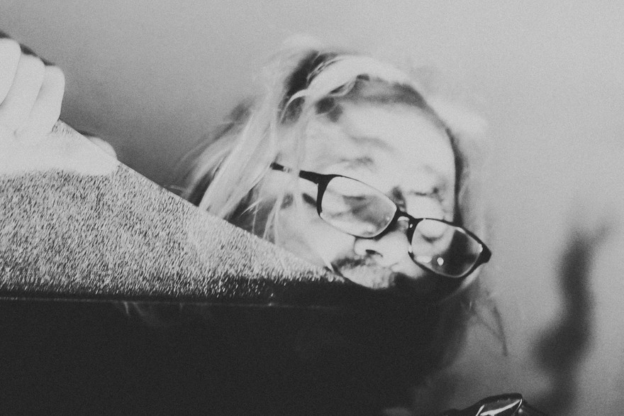 Experimental performer Granpa (Lucas Abela) is holding a large piece of glass pressed against his lips, with a modular synthesizer in frame.