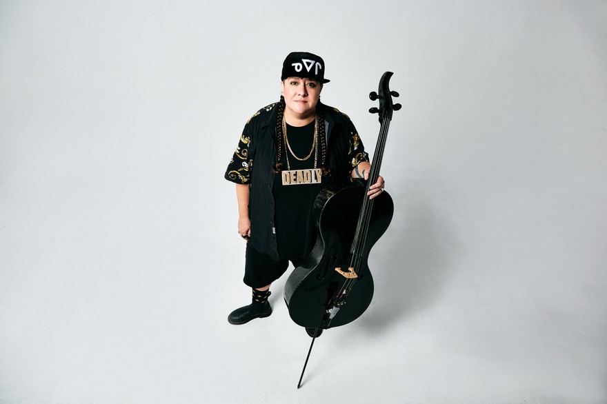 Photo shot from above of Chris Derksen holding a cello, looking up toward the camera.