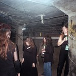A candid colour photo shows five-piece group Babe Corner standing under a dingey concrete structure. Several members are holding cans of beer. 