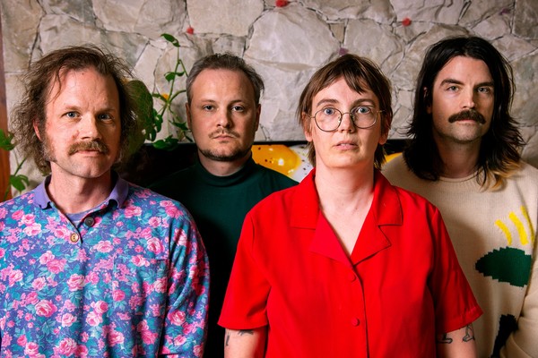 A vibrant colour photo of four-piece Bananahaus standing in front of a stone wall.