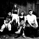 A black and white photo shows four-piece Big Rig posing on a couch in an indoor setting.  