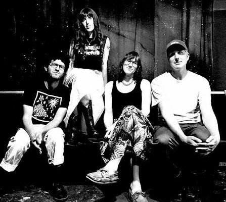A black and white photo shows four-piece Big Rig posing on a couch in an indoor setting.  