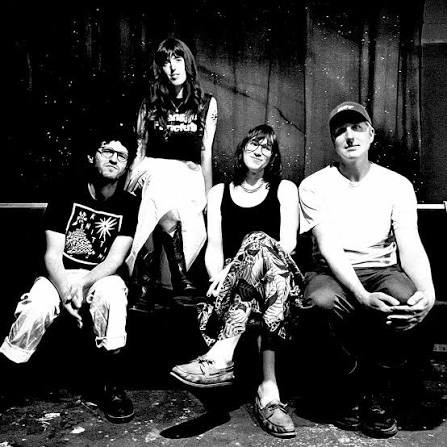A black and white photo shows four-piece Big Rig posing on a couch in an indoor setting.  