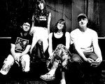 A black and white photo shows four-piece Big Rig posing on a couch in an indoor setting.  