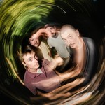 A swirly long exposure colour photo show four-piece group Cistern posing. 