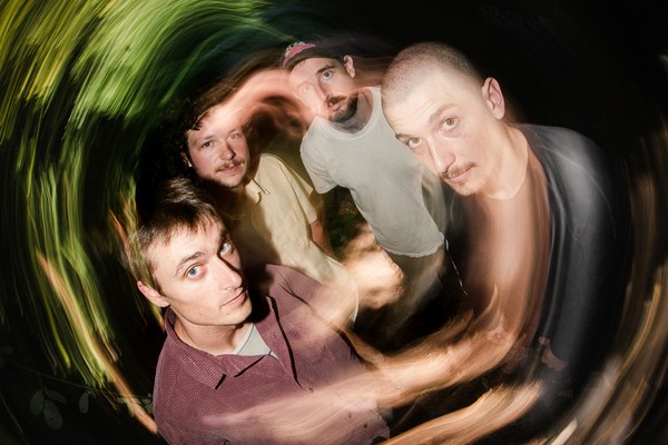 A swirly long exposure colour photo show four-piece group Cistern posing. 