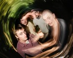 A swirly long exposure colour photo show four-piece group Cistern posing. 