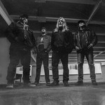 A black and white photo shows four-piece band Culled standing in large concrete parkade.