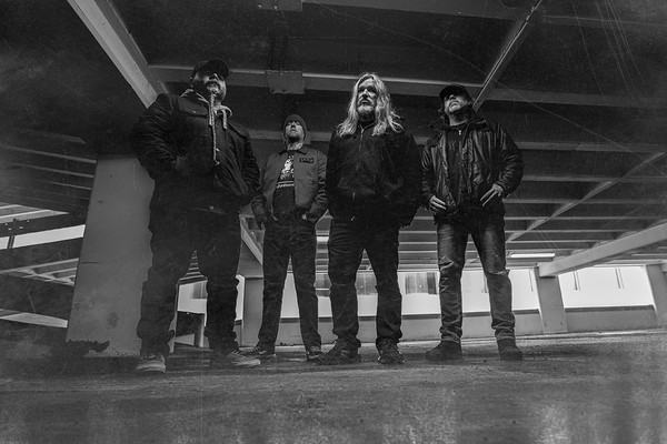 A black and white photo shows four-piece band Culled standing in large concrete parkade.