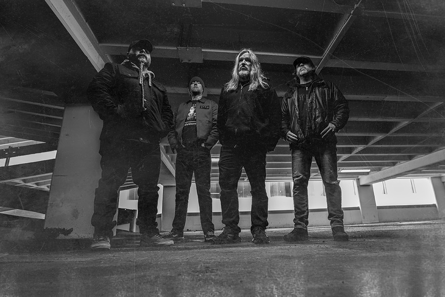 A black and white photo shows four-piece band Culled standing in large concrete parkade.