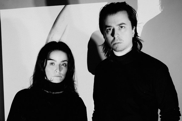 A black and white photo shows duo Dermabrasion standing in a white room wearing all black.