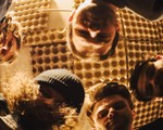 A hazy photo taken from below shows five-piece band looking down at the camera with a golden roof above that appears to be lined with egg cartons. 