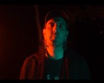 A close-up colour photo of artist ECHTHROS standing outside at night with blue and red light shining on their face. 