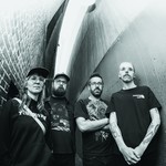 A black and white photo taken from below shows four-piece group False Body posing in an alleyway wearing black clothes. 