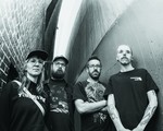 A black and white photo taken from below shows four-piece group False Body posing in an alleyway wearing black clothes. 