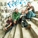 A colour photo shows four-piece group innerouter sitting outside on concrete stairs, with each member on a different step.The setting that resembles the enrtrance to an old train station, graffiti fills the concrete wall behind them.