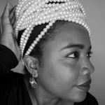 A close-up photo shows artist MAGELLA looking sideways with a long string of white pearls strung around the top of their head. 