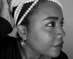 A close-up photo shows artist MAGELLA looking sideways with a long string of white pearls strung around the top of their head. 