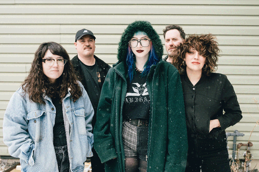 A colour photo shows five-piece group Midnight Peg standing outdoors on a winter day