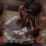 A double exposure photo shows frontperson of the project mon cher playing a white electric guitar and singing into a microphone. 