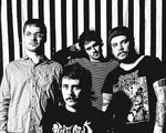 A fuzzy black and white photo shows four-piece Pnoom posing in front of a black and white striped wall. 