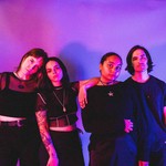 The four-piece group Roach are shown standing in a line wearing all black against a purple background. 