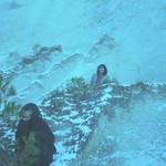 A colour photo shows two members of TANGINGUGUN standing spread out on a snowy mountain landscape. 