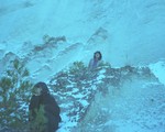 A colour photo shows two members of TANGINGUGUN standing spread out on a snowy mountain landscape. 