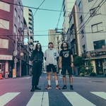 A colour photo featuring three members of Weep Wave, posed standing in a Japanese intersection in an urban setting. 