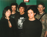A colour photo of five-piece Witch Victim standing in a green hallway, each facing the camera. Exit sign is above them.