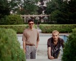 A colour photo of duo World News posed outdoors with an empty pool and hedge bushes in the background. 