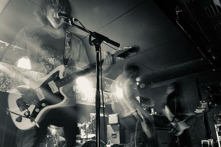 A black and white photo of four-piece Yarbo performing in a dimly lit venue.